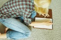 The woman sits on the carpet and writes Royalty Free Stock Photo