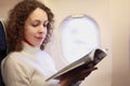 Woman sits in chair nea illuminator of airplane