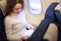 Woman sits in chair near illuminator of airplane