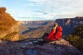 Woman sits at cliff edge and takes in magnificent mountain views