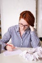 Woman sits at a desk in front of a blank sheet of paper with a red pencil Royalty Free Stock Photo