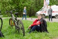 Woman sits on the grass next to a bicycle waiting for the start of the competition