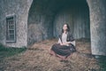 A woman sits on the hay in a vintage town in medieval Europe