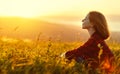 Woman sits with her back in the field and look sunset in the mountains Royalty Free Stock Photo
