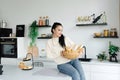 A woman sits in her kitchen holding a bread basket. Enjoying the little things. Lykke Concepts. Relaxation Concepts