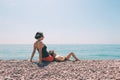 A woman sits with her son on the beach and looks at the sea