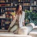 Woman sits at home with open book and looks thoughtfully away. Royalty Free Stock Photo