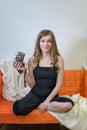 Woman sits with legs on the couch and holds in her hand an antique camera. copy space on the wall above her