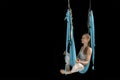 Woman sits in lotus pose in hammock practicing aerial yoga black background. Copy space. Anti-gravity yoga Royalty Free Stock Photo