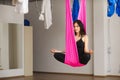 Woman sits in lotus pose in hammock practicing aerial yoga Royalty Free Stock Photo