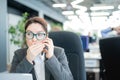 A woman sits in an office at her desk and gossips on the phone. Corporate ethics. Female employee in a suit tells