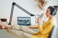 Woman sits with put your feet on table and recording podcast at his small cozy radio studio