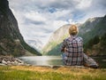 A woman sits on the shore of a picturesque fjord in Norway, admiring the beauty of Scandinavian nature Royalty Free Stock Photo