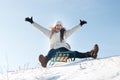 Woman sits and sledges from the mountain against the background of snow and sky in winterGirl laughs and rejoices in snow,