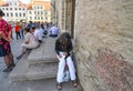 A woman sits on the steps of the Tallinn Town Hall building in Old Town Square writing postcards in Tallinn Estonia