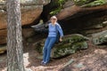 A woman sits on a stone under overhanging rocks.