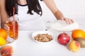 Woman sits at a table and eat breakfast. Women eating healthy food for breakfast. Fruit, cereal and milk, close up selective focus