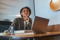 A woman sits at a table with a laptop, a whitecollar worker at an event