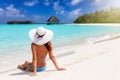 Woman sits on a tropical paradise beach in the Maldives islands