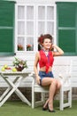 Woman sits at white wooden table near house with windows Royalty Free Stock Photo