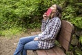 Woman sits on a wooden bench in a forest park by the path and lo Royalty Free Stock Photo