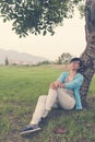 Woman sitting against tree