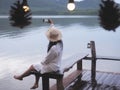 woman sitting alone on the bench taking photograph at sunrise beach background Royalty Free Stock Photo