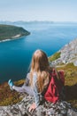 Woman sitting alone on cliff edge travel with backpack