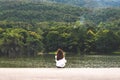 A woman sitting alone by the lake looking at the mountains with cloudy and green nature Royalty Free Stock Photo