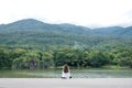 A woman sitting alone by the lake looking at the mountains with cloudy and green nature Royalty Free Stock Photo