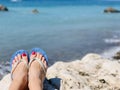 A woman sitting alone on stone near the sea with her feet pointing down Royalty Free Stock Photo