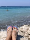 A woman sitting alone on stone near the sea with her feet pointing down Royalty Free Stock Photo