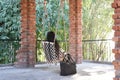 A woman sitting alone on a swing amidst of pillars made up of bricks at sunrise Royalty Free Stock Photo