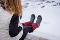 Woman sitting on edge of pier in winter with red plaid boots Royalty Free Stock Photo