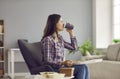 Woman sitting in armchair at home, drinking coffee and eating salad from takeaway delivery Royalty Free Stock Photo