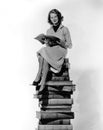 Woman sitting atop pile of books