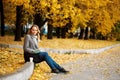 Woman sitting in autumn city park with golden trees Royalty Free Stock Photo