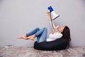 Woman sitting on bag chair and screaming in megaphone at herself Royalty Free Stock Photo