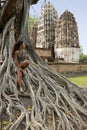 Woman sitting banyan roots tree sukhothai Thailand