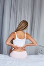 Woman sitting on a bed with back pain Royalty Free Stock Photo