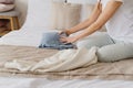 Woman sitting on bed and organizing fall and winter warm clothing.