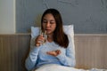 Woman sitting on bed with sleeping pill in hand for insomnia or melatonin. Sickness female take a medicine for headache or Royalty Free Stock Photo