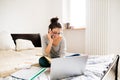 Woman sitting on bed, working on laptop, calling. Home office. Royalty Free Stock Photo