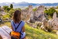 Woman sitting bench above ruins.