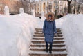 Woman goes down on a snowy ladder, staircase. Winter park in the city during the day in snowy weather with falling snow. Royalty Free Stock Photo