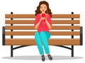 Lady in headpones sitting on bench, listening to music and browsing social media on smartphone Royalty Free Stock Photo