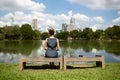 Woman sitting on a bench and looking at lake in city park Royalty Free Stock Photo