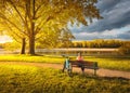 Woman sitting on bench and mountain bike, yellow trees and lake