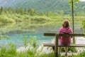 Woman is sitting on bench near lake in Austria near Alps