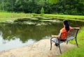 Woman sitting on the bench, near lake